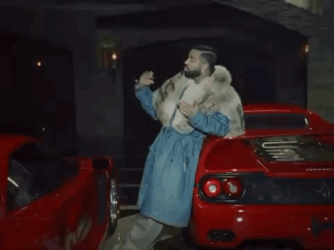 Man in Fur Coat Next to Red Sports Car