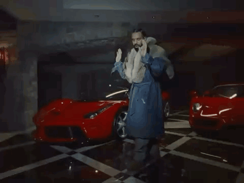 Man in Fur Coat Next to Two Red Sports Cars