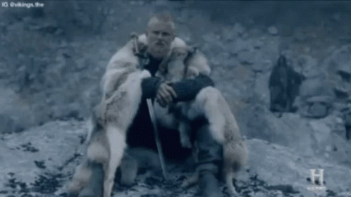 Man In Fur Coat Sitting On Rock Holding Sword GIF