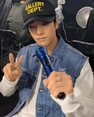 Man In Gallery Dept Hat Holding Microphone GIF