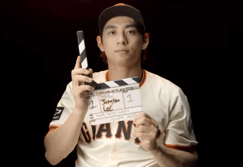 Man in Giants Jersey Holding Clapper Board
