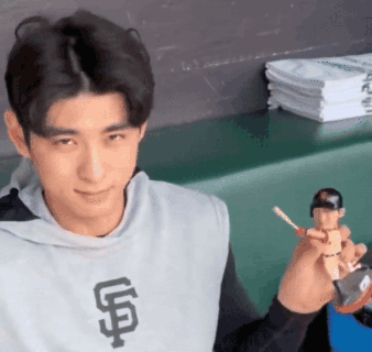 Man in Giants Shirt Holding Baseball Figurine