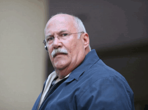 Man in Glasses and Blue Jacket Looking at Camera