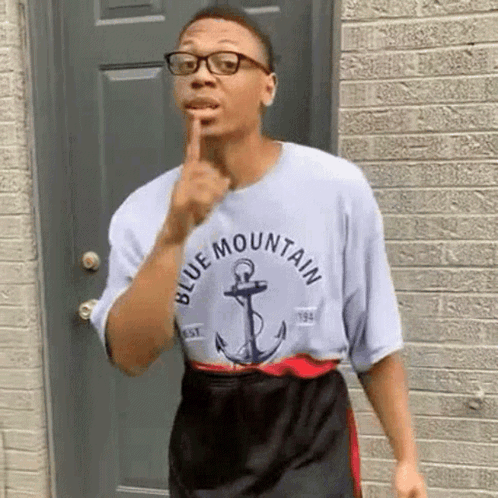 Man In Glasses And Blue Mountain T-Shirt In Front Of Brick Building GIF