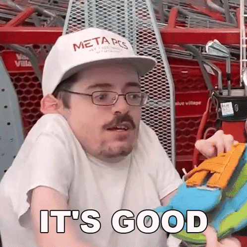 Man in Glasses and Hat Holding Toy Saying It's Good