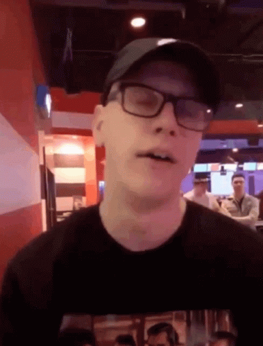 Man in Glasses and Hat Looks at Camera