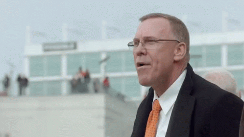 Man in Glasses and Orange Tie at Large Building