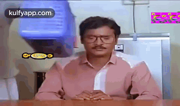 Man In Glasses And Pink Shirt Sitting At Table GIF