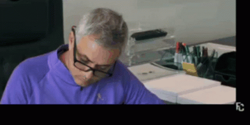 Man in Glasses and Purple Shirt Sitting at Table