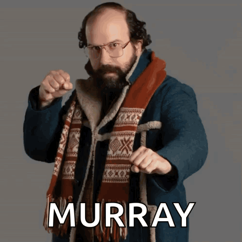 Man in Glasses and Scarf Pointing at Camera Murray