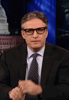 Man In Glasses And Suit Sitting In Front Of Building GIF