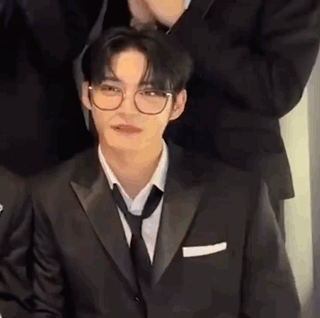 Man in Glasses and Suit Sitting With Group