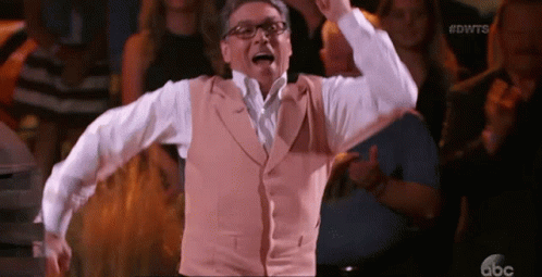 Man in Glasses and Vest Dancing Before Crowd