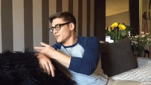 Man In Glasses Sitting On Couch With Flowers GIF