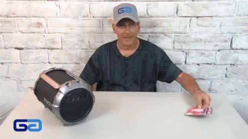 Man in Go Hat Sitting at Table Next to Boombox