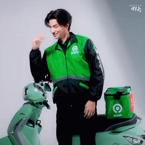 Man in Gojek Jacket Next to Green Scooter