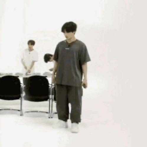 Man in Gray and Black Walking Past Chairs