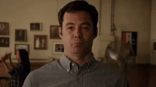 Man in Gray Shirt Making Funny Face with Woman Behind