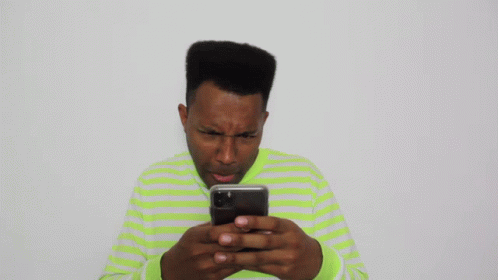 Man in Green and White Striped Shirt Looking at Cell Phone