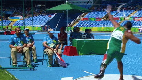 Man in Green and Yellow Uniform Throwing Shot Put