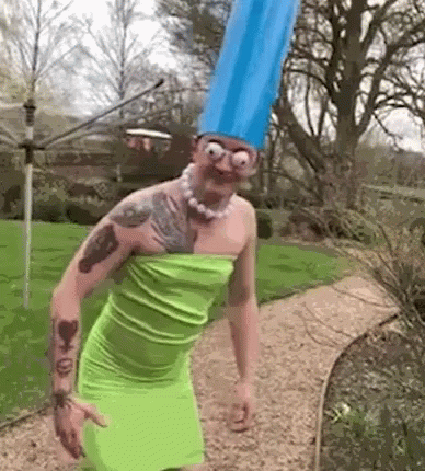 Man In Green Dress And Blue Hat Standing In Garden GIF