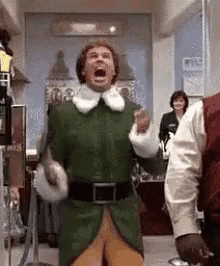 Man In Green Elf Costume Standing In Hallway GIF