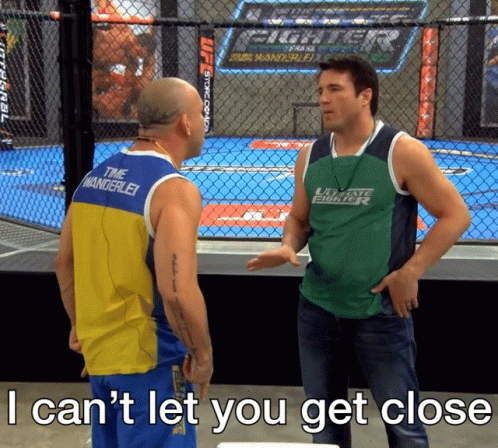 Man in Green Fighter Shirt Talking to Tank Top Man