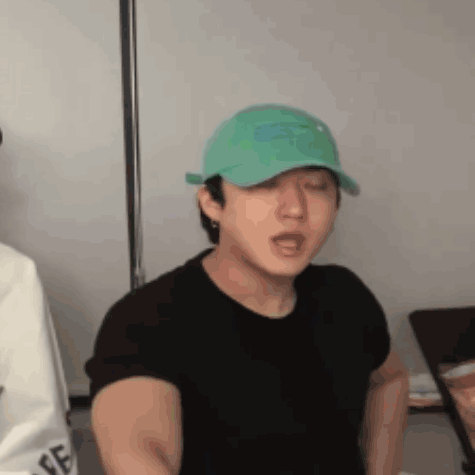 Man in Green Hat and Black Shirt with Eyes Closed