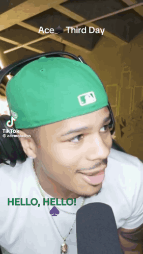 Man in Green Hat and Headphones Talking Into Microphone