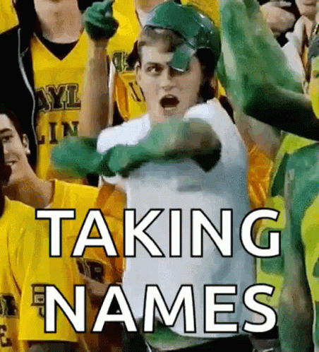Man in Green Helmet Taking Names in Front of Crowd