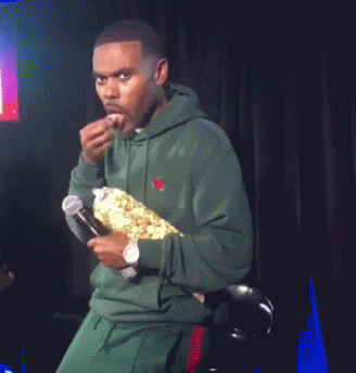 Man in Green Hoodie Holding Microphone and Popcorn