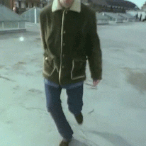 Man in Green Jacket and Blue Jeans on Rooftop
