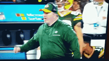Man in Green Jacket and Hat in Front of Fox NFL Sign