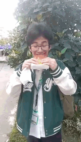 Man in Green Jacket Eating Hamburger