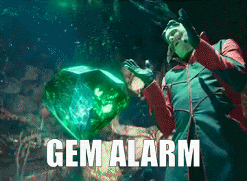 Man in Green Jacket Holding Large Emerald Gem Alarm