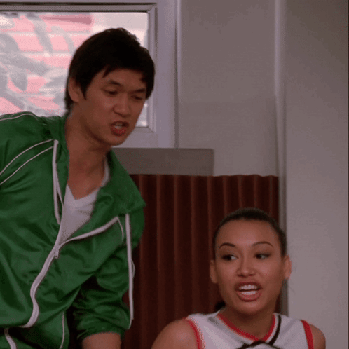 Man in Green Jacket Next to Cheerleader