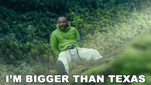 Man In Green Jacket On Cliff Saying I'm Bigger Than Texas GIF