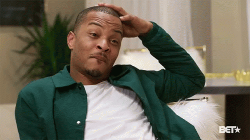 Man in Green Jacket Scratching Head on Couch