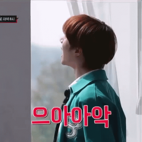 Man in Green Jacket Standing in Front of Window with Korean Writing