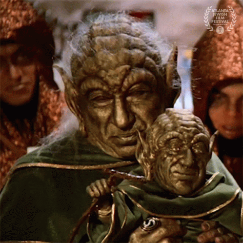 Man in Green Robe Holding Puppet