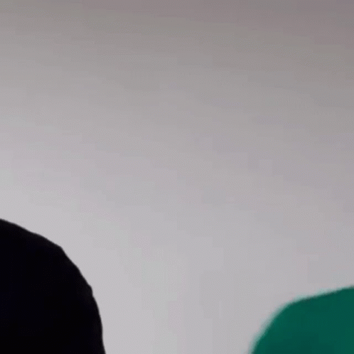 Man In Green Shirt And Black Hat Next To Man In Black Shirt