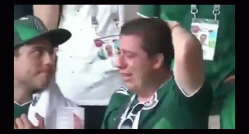 Man in Green Shirt Crying in Stadium with Onlooker