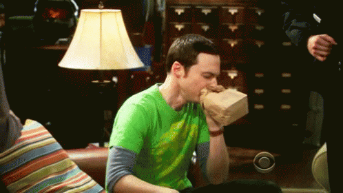 Man in Green Shirt Eating Food on Couch