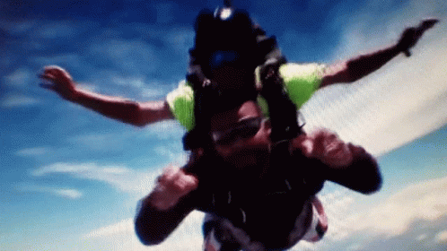 Man in Green Shirt Flying Through Blue Sky