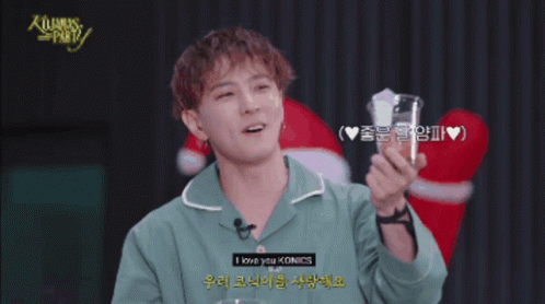 Man in Green Shirt Holding Glass Saying Merry Christmas