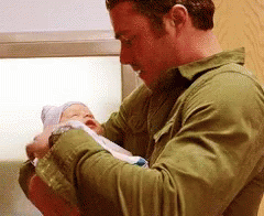 Man in Green Shirt Holding Newborn Baby