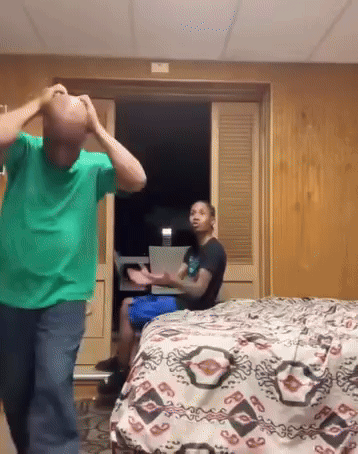 Man in Green Shirt in Front of Bed