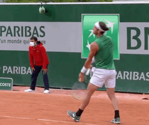 Man in Green Shirt Playing Tennis in Front of Paribas Banner