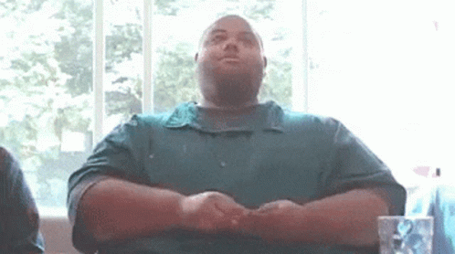 Man In Green Shirt Sitting With Folded Hands GIF