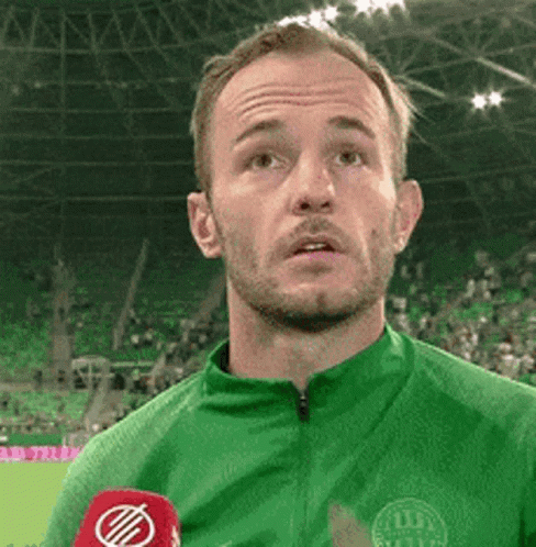 Man in Green Shirt Talking Into Microphone